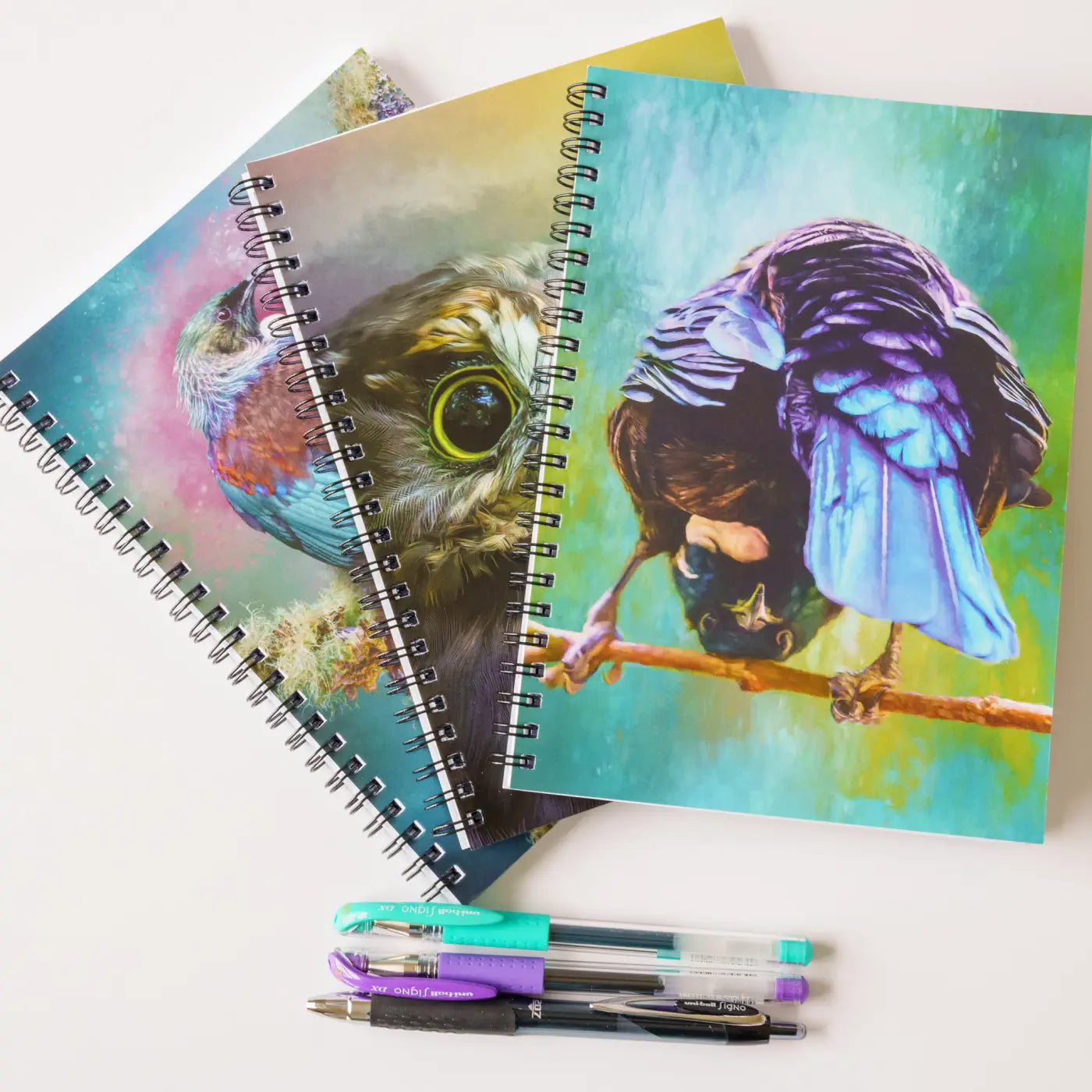 three notebooks with pens with bird designs on the covers