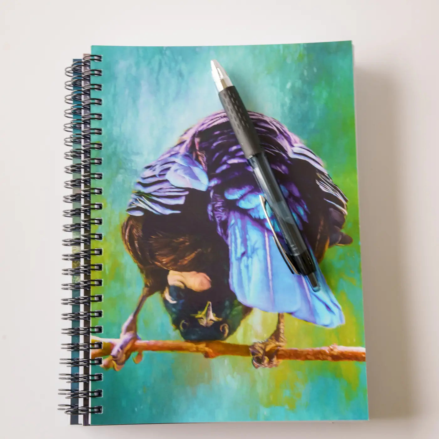 stack of three tui notebooks with a pen