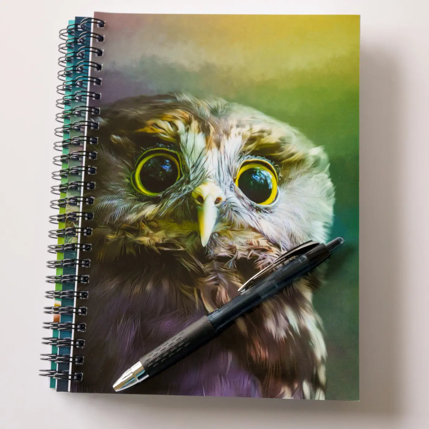 a stack of three notebooks and a pen