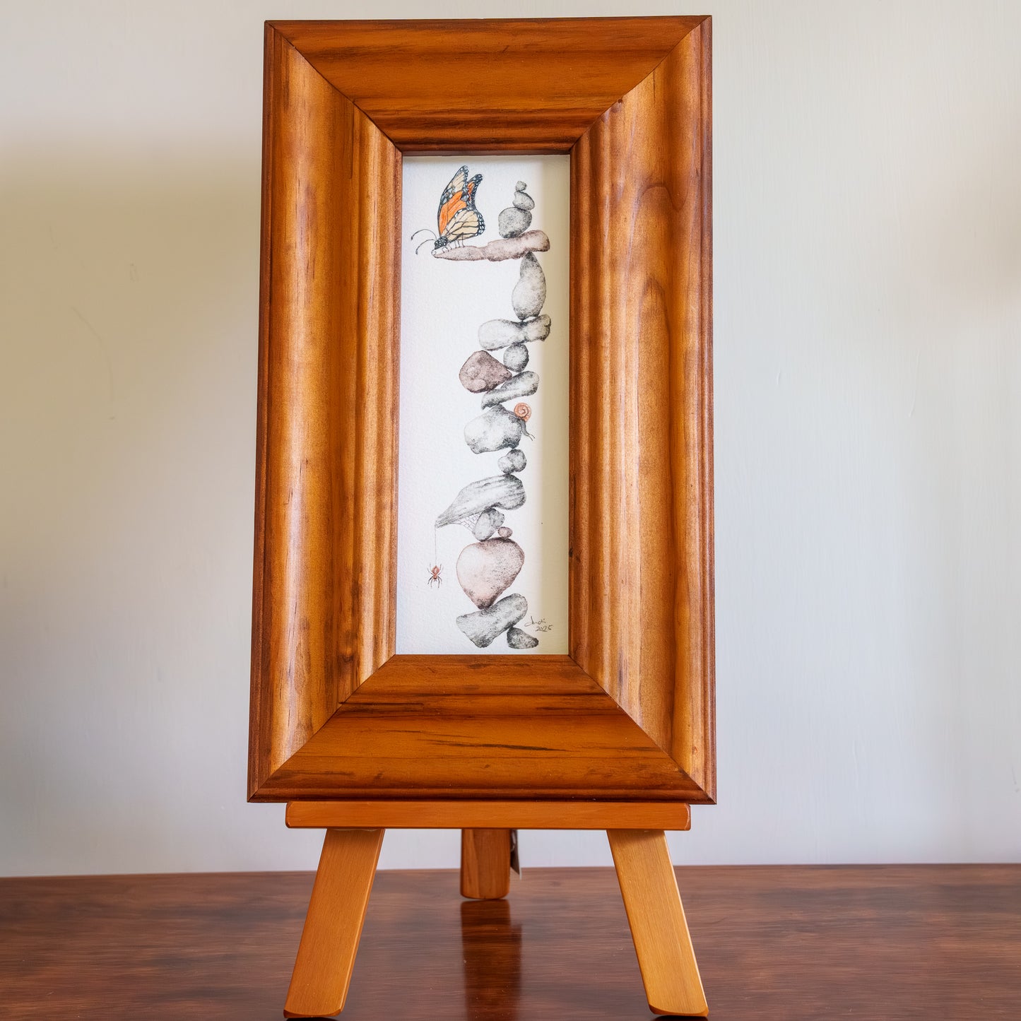 Wooden frame with a painting of stacked stones on a white background