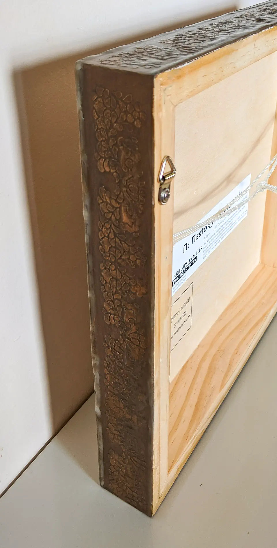 Side and back view of artwork showing embossed sides of cradleboard and hanging hardware