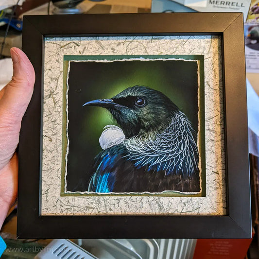 Judi holding a framed tui artwork