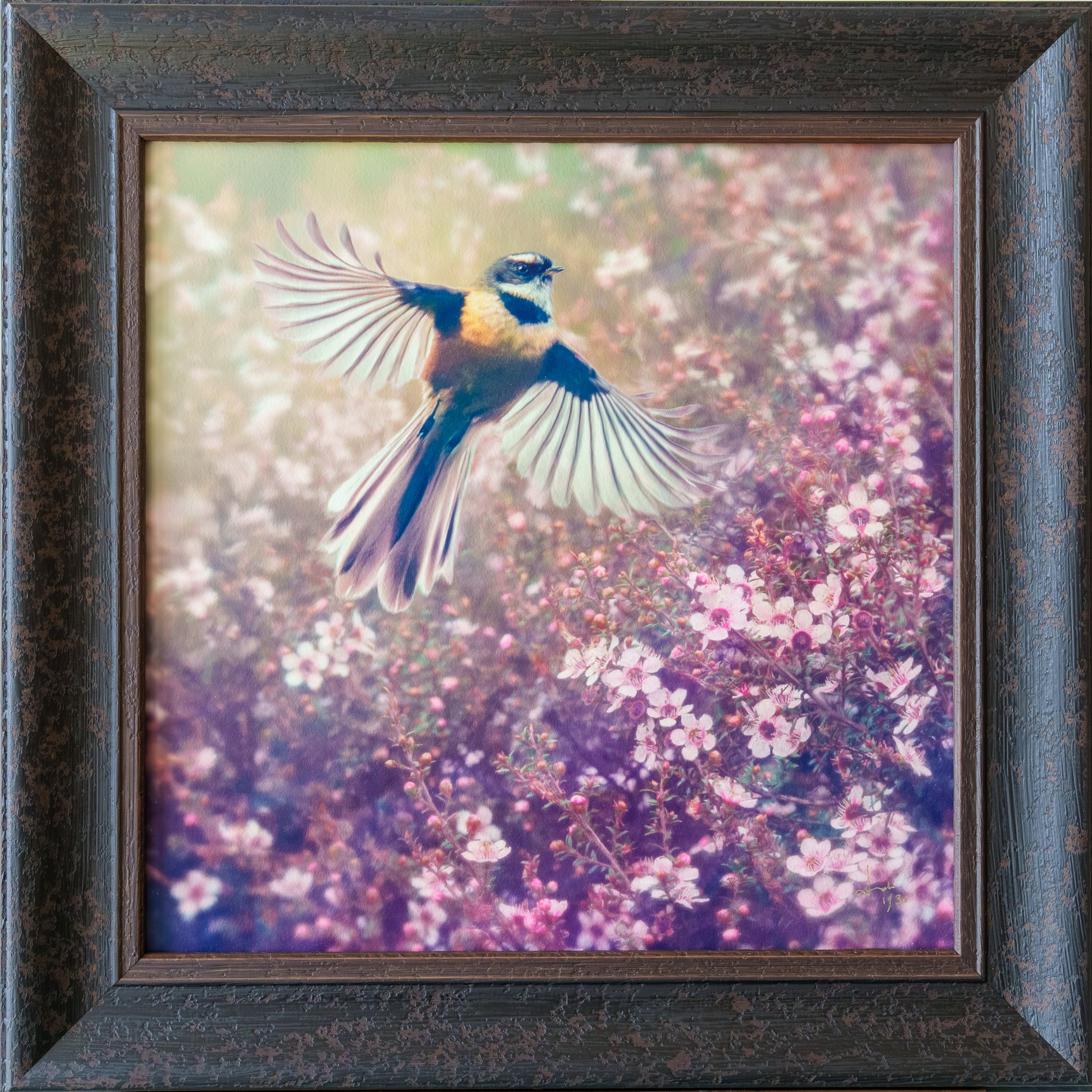 Framed square wall art featuring a small bird in flight over pink and purple flowering plants, set in a dark textured wooden frame.