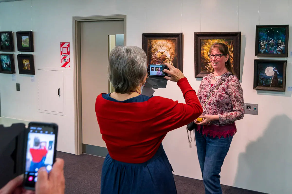 Photo of Eugene Sage photographing Judi in front of her art