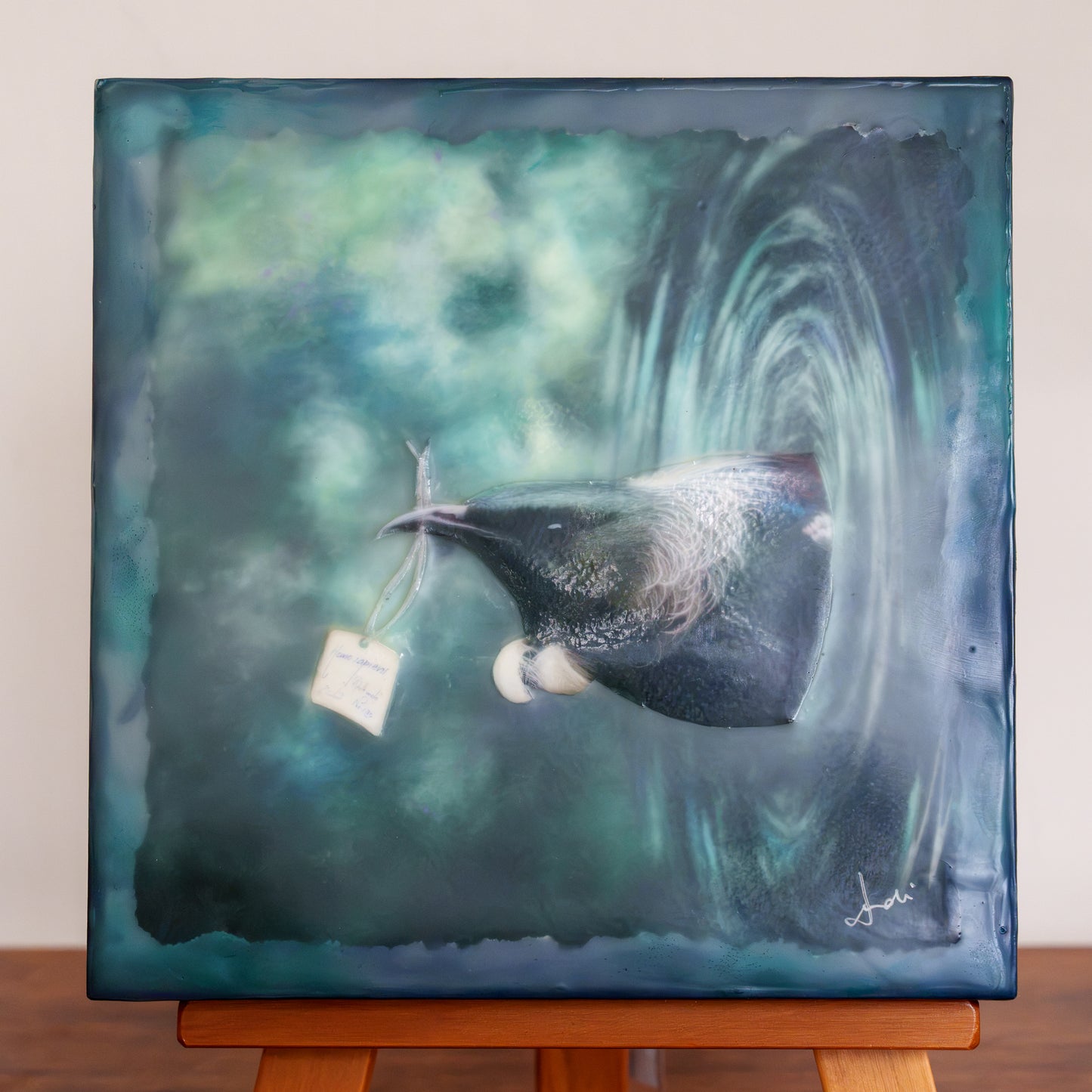 Wax finished mixed media artwork of a tui coming out of a vortex carrying a specimen label in his beak.