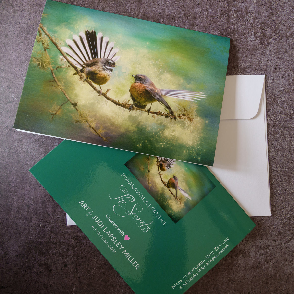 Greeting cards and an envelope featuring two fantail piwakawaka birds on a lichened branch.