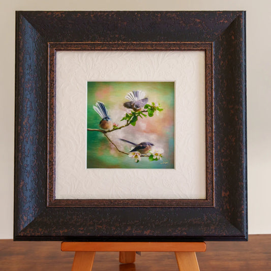 Framed artwork of birds on a branch with a textured white mat