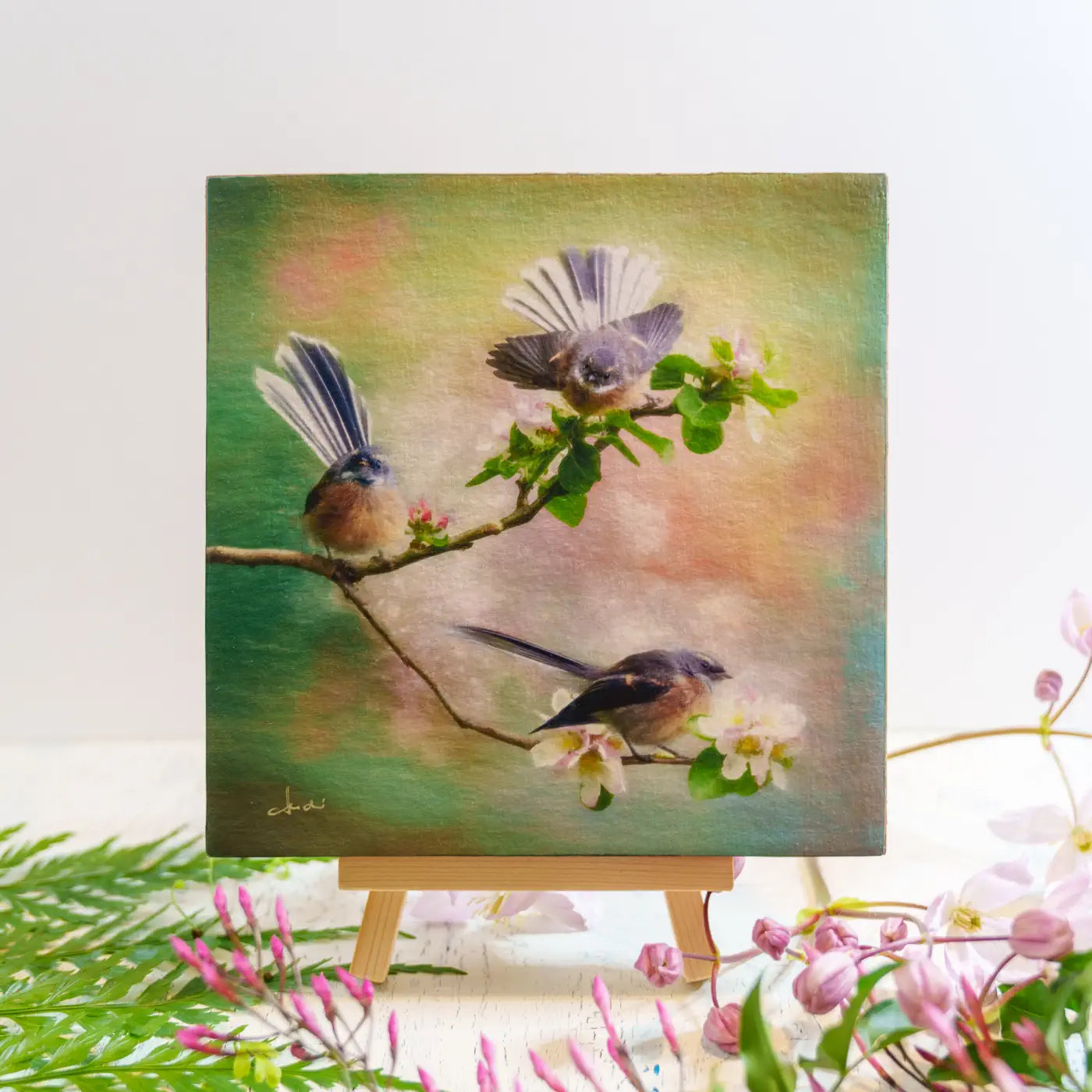 Artwork of three birds on a branch sitting on an easel