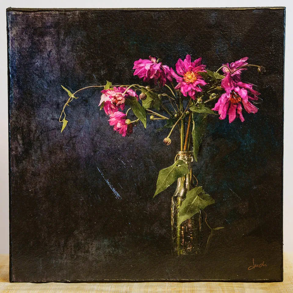 Photo of a mounted artwork of flowers in a bottle with a dark textured background