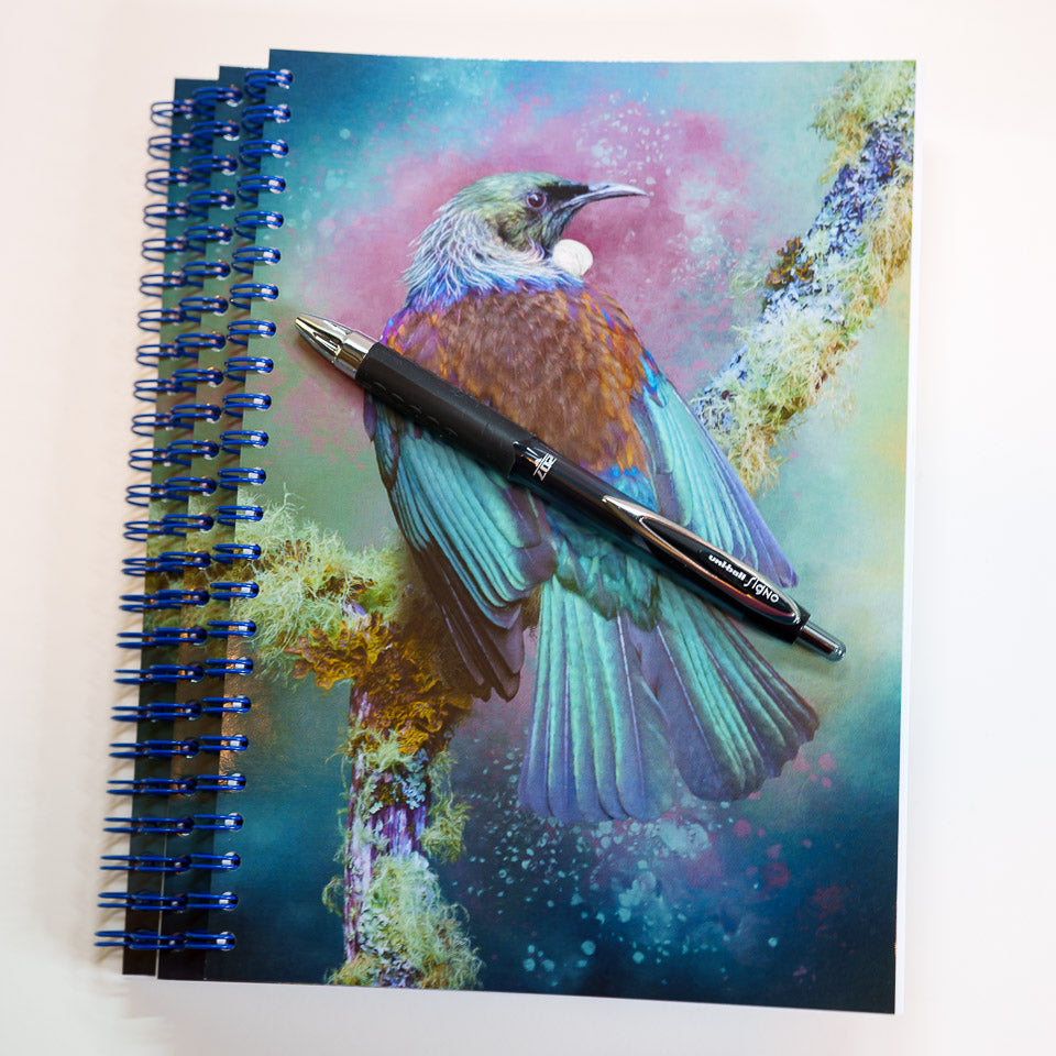Three tui notebooks, stacked, with one pen