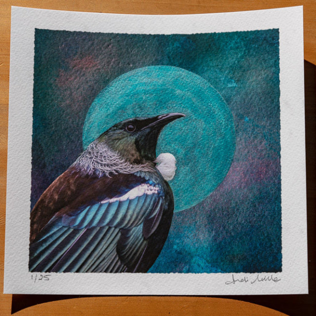 embellished print showing artwork of a tui with an aqua pearlescent moon or halo surround it